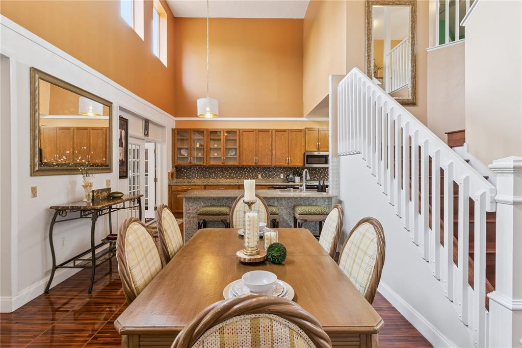 A dining area with a wooden table and chairs sits before an open kitchen — 2606 ROYAL FERN PLACE, KISSIMMEE, FL