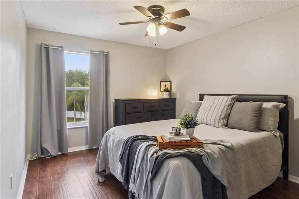 A bedroom features dark wood flooring, a ceiling fan, a dresser, and a bed — 2606 ROYAL FERN PLACE, KISSIMMEE, FL
