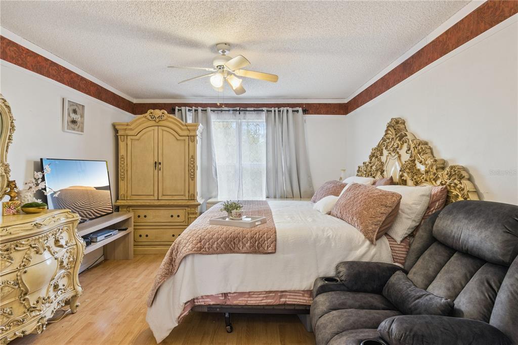 A bedroom features a large ornate headboard, a wooden armoire, and a gray recliner — 2606 ROYAL FERN PLACE, KISSIMMEE, FL