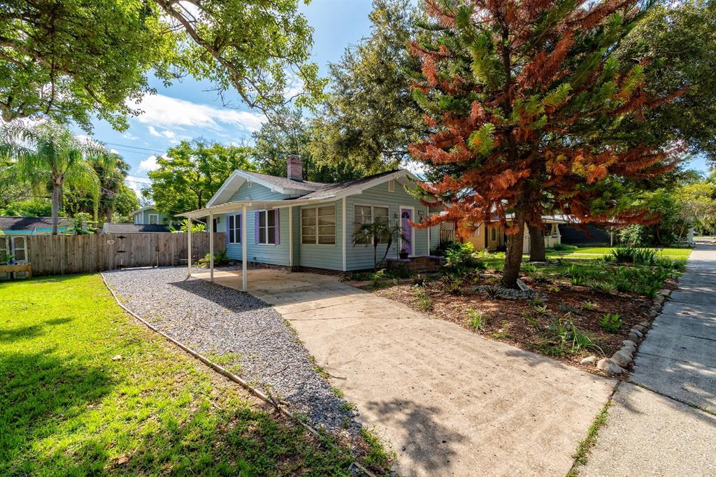 A light blue house with a carport, gravel driveway, and a large tree in the yard — 1919 S PALMETTO AVENUE, SANFORD, FL