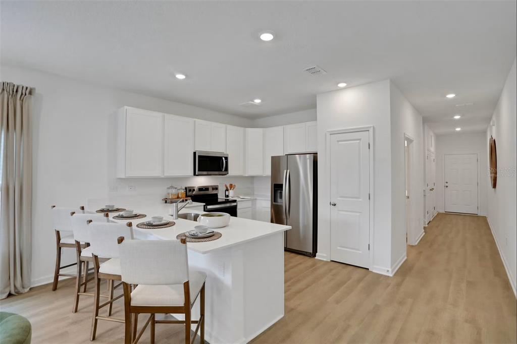A modern kitchen features white cabinets, stainless steel appliances, and a central island with seating — 7646 COMMANDER LANE, JACKSONVILLE, FL