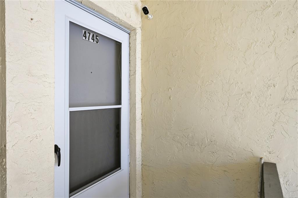 A white storm door with the number 4745 is mounted on a textured beige exterior wall — 4745 AVON COURT UNIT 4745, ST CLOUD, FL