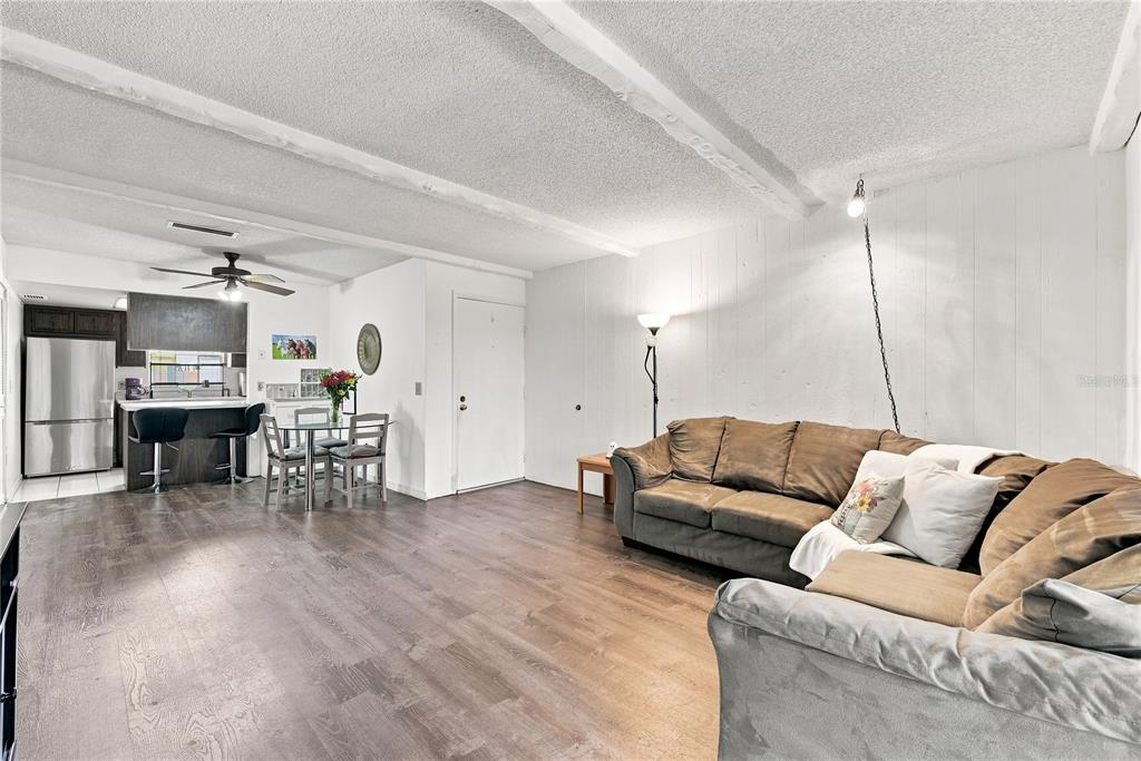 A living room and dining area feature wood-look flooring, white walls, and a brown sectional sofa — 4745 AVON COURT UNIT 4745, ST CLOUD, FL
