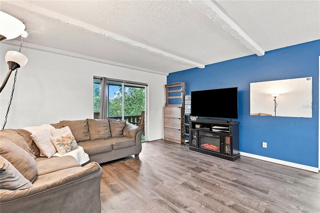 A living room features a grey sectional sofa, wood-look flooring, and a blue accent wall — 4745 AVON COURT UNIT 4745, ST CLOUD, FL