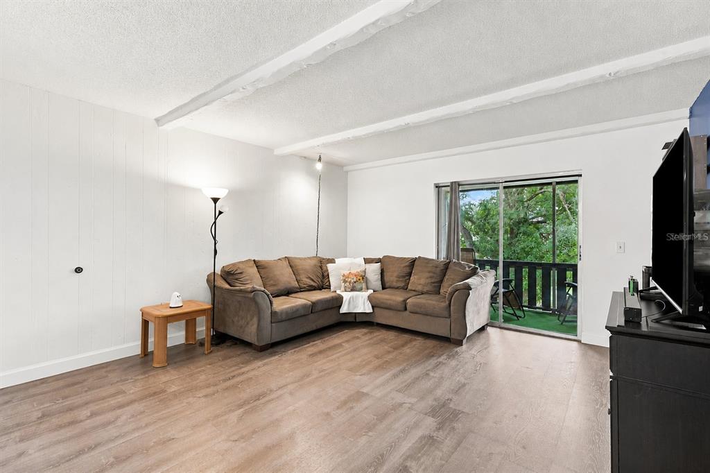 A living room with wood-look flooring, a brown sectional sofa, and a sliding glass door — 4745 AVON COURT UNIT 4745, ST CLOUD, FL