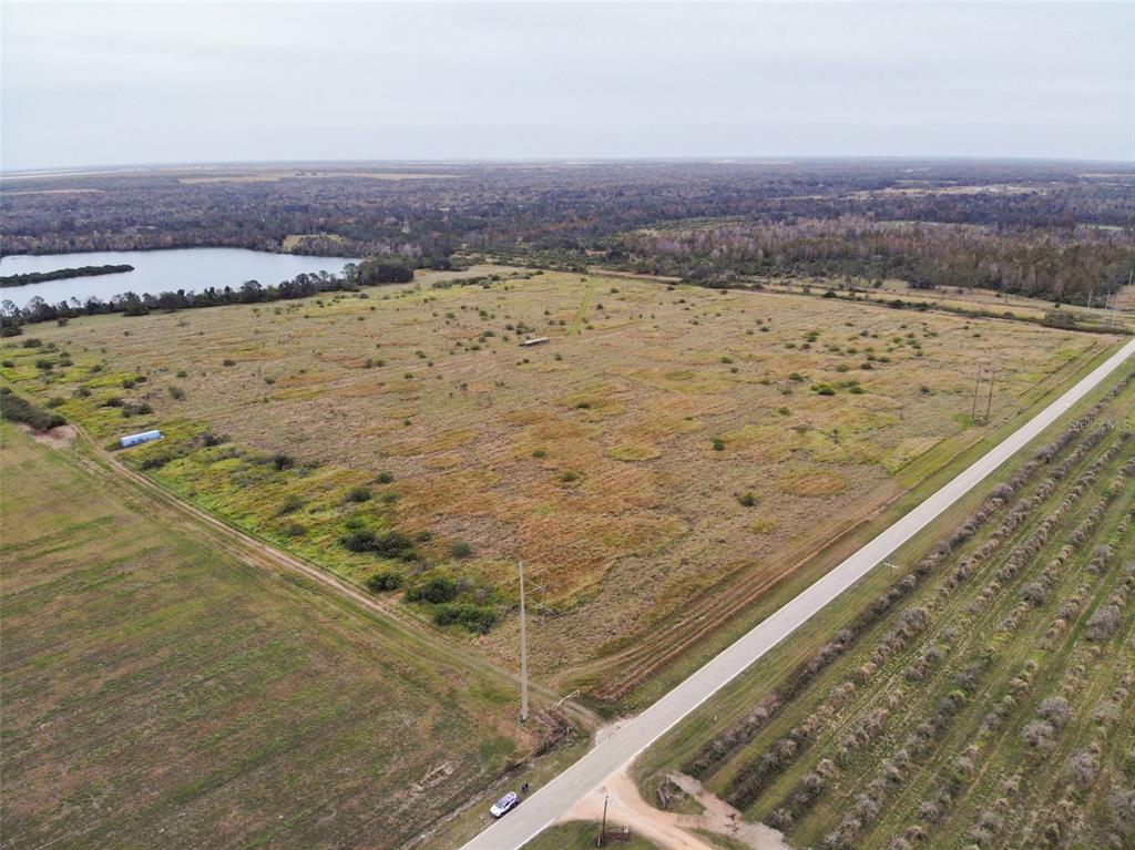 An aerial view shows a large, flat, grassy field bordered by a road and a lake — OLD BOWLING GREEN ROAD, FORT MEADE, FL