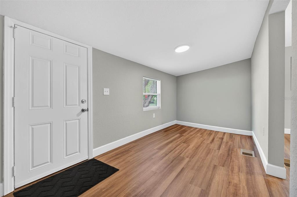 A view from a doorway into a living room with wood-look flooring and light walls — 305 S SHARP STREET, LAKE WALES, FL