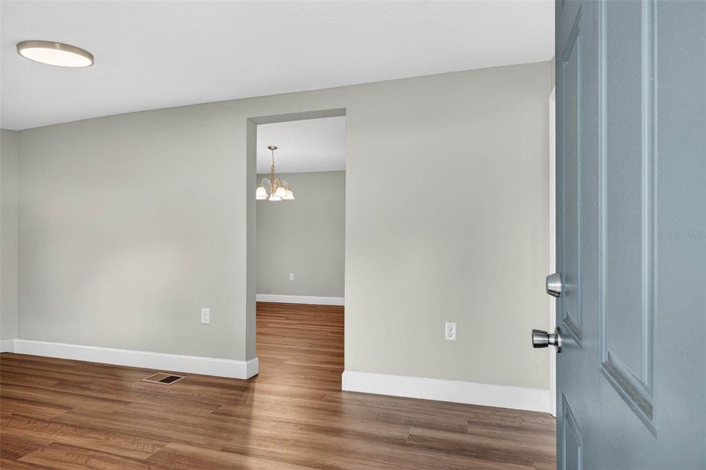 An empty room with light gray walls, wood-look flooring, and a window — 305 S SHARP STREET, LAKE WALES, FL