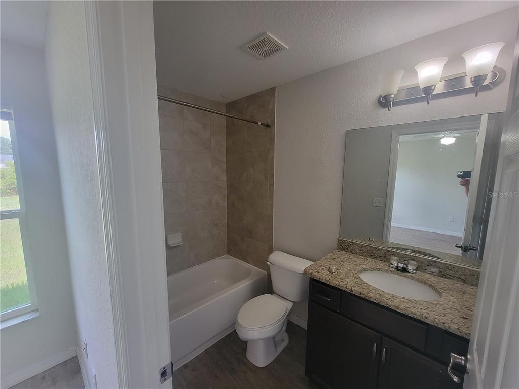 A bathroom features a tub-shower combo with tiled walls, a toilet, and a granite vanity — 42 JUNIPER LOOP CIRCLE, OCALA, FL