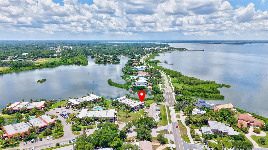 An aerial view shows a multi-story apartment building with a parking lot and lake — 1001 S BAYSHORE BOULEVARD UNIT 101, SAFETY HARBOR, FL