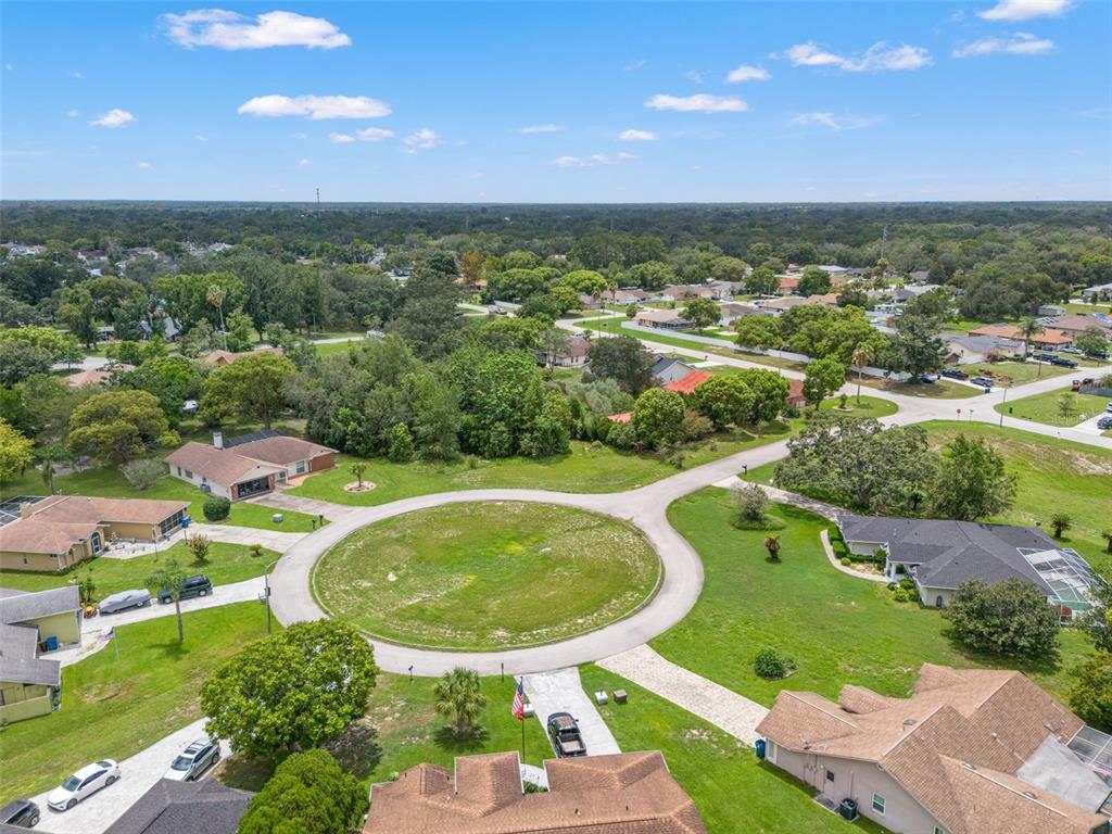 An aerial view shows a residential cul-de-sac surrounded by houses, trees, and green lawns — NORTHWIND COURT, SPRING HILL, FL