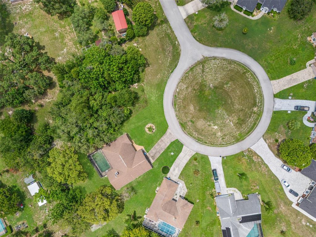 An aerial view shows several houses with swimming pools situated around a circular cul-de-sac — NORTHWIND COURT, SPRING HILL, FL