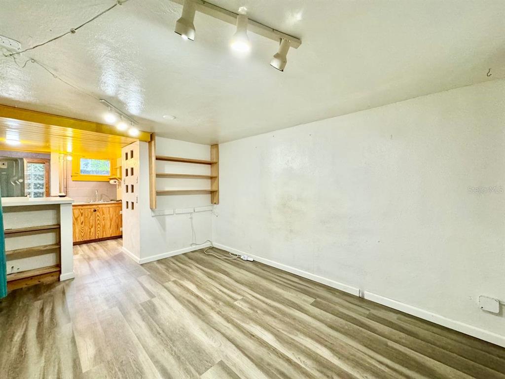 A room with wood-look flooring, white walls, open shelving, and a view into a kitchen — 6601 N NAVIN AVENUE UNIT A, TAMPA, FL