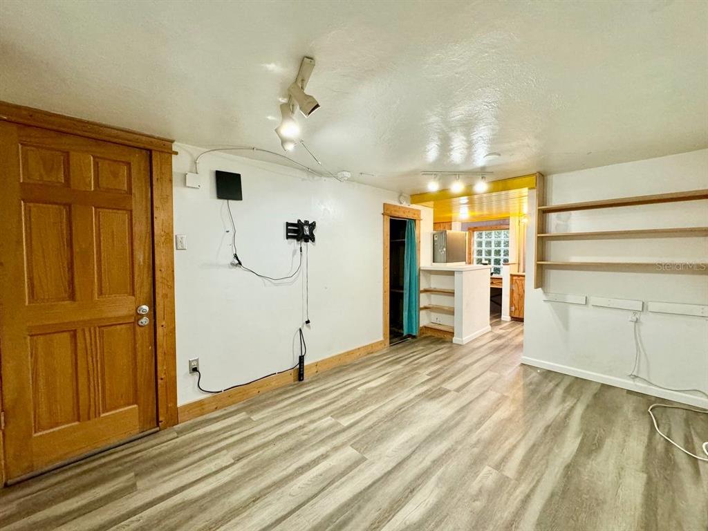 An interior room features wood-look flooring, white walls, a wooden door, and open shelving — 6601 N NAVIN AVENUE UNIT A, TAMPA, FL