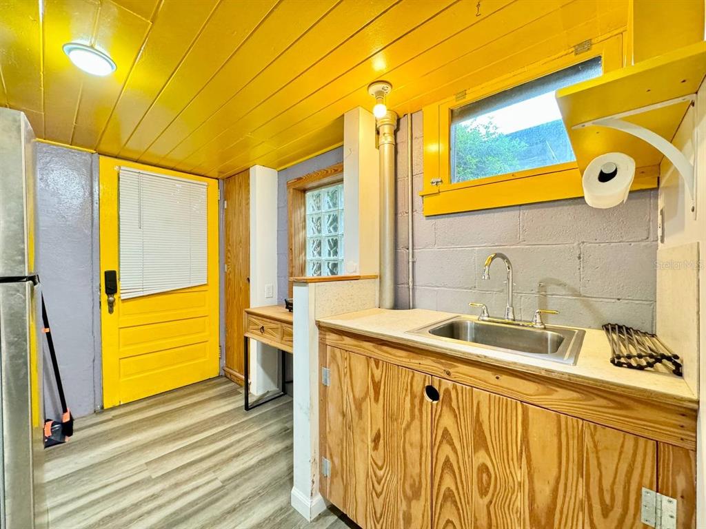 A kitchen with yellow wood-paneled ceilings, a sink, wooden cabinets, and a yellow door — 6601 N NAVIN AVENUE UNIT A, TAMPA, FL