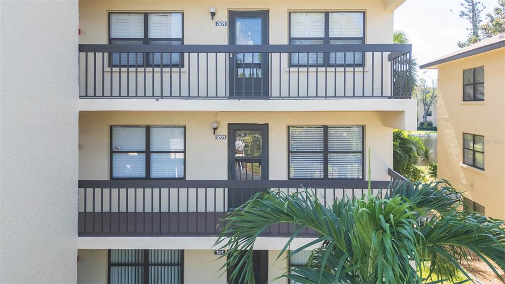 A three-story apartment building exterior features balconies with dark railings and numbered unit doors — 315 30 AVENUE W UNIT B201, BRADENTON, FL