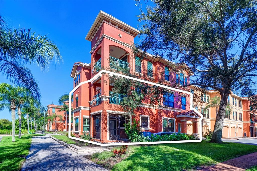A three-story orange stucco apartment building with balconies and a screened-in ground floor patio — 2757 VIA CIPRIANI UNIT 1114A, CLEARWATER, FL