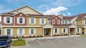 An exterior view of a multi-story apartment building with yellow siding and a parking lot — 7512 SUNFLOWER CIRCLE, KISSIMMEE, FL
