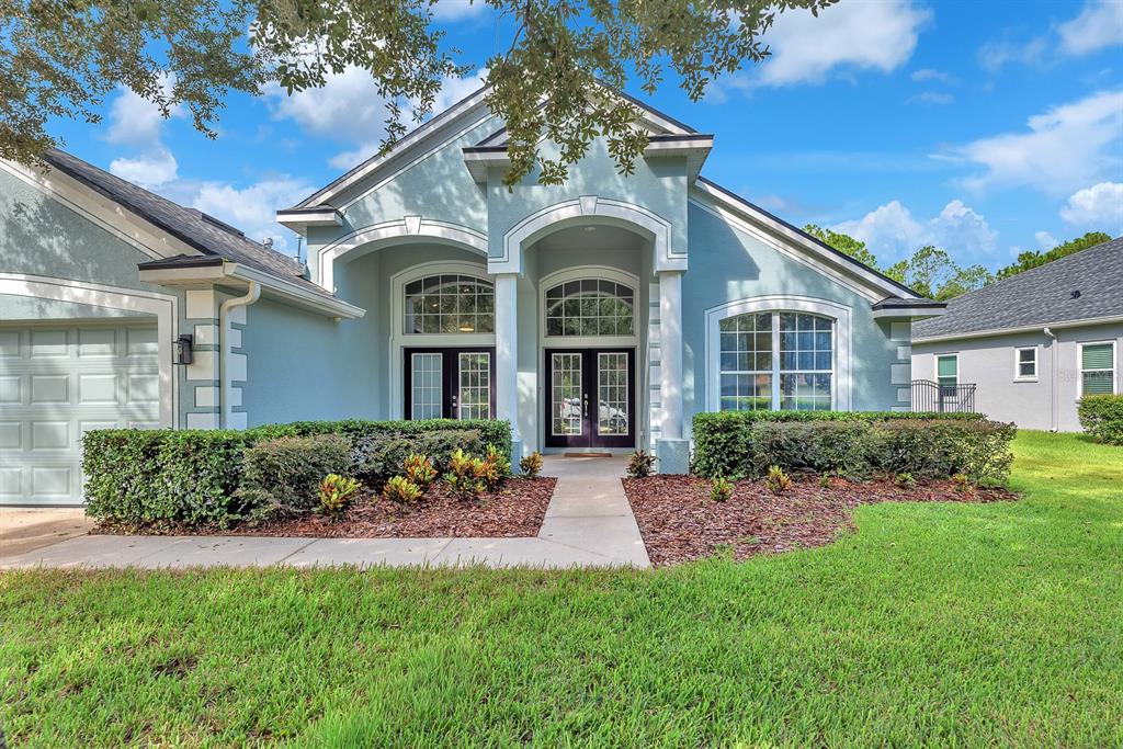 A light blue single-story house with a double front door and a manicured front lawn — 16405 BRIDGEWALK DRIVE, LITHIA, FL
