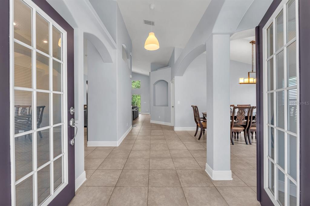 A view from an entryway into a tiled hallway with arched openings and a dining area — 16405 BRIDGEWALK DRIVE, LITHIA, FL