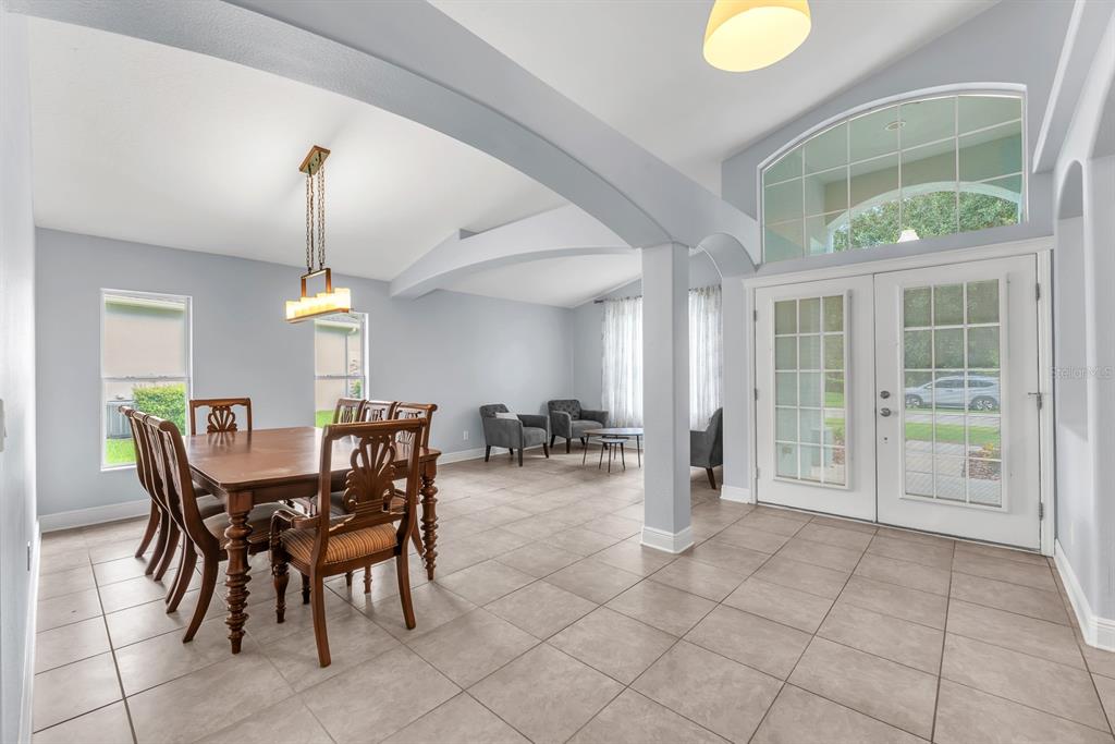 A dining area with a wooden table and chairs sits near an entryway with glass doors — 16405 BRIDGEWALK DRIVE, LITHIA, FL