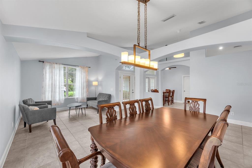 A dining room with a wooden table and chairs sits in front of a living area — 16405 BRIDGEWALK DRIVE, LITHIA, FL