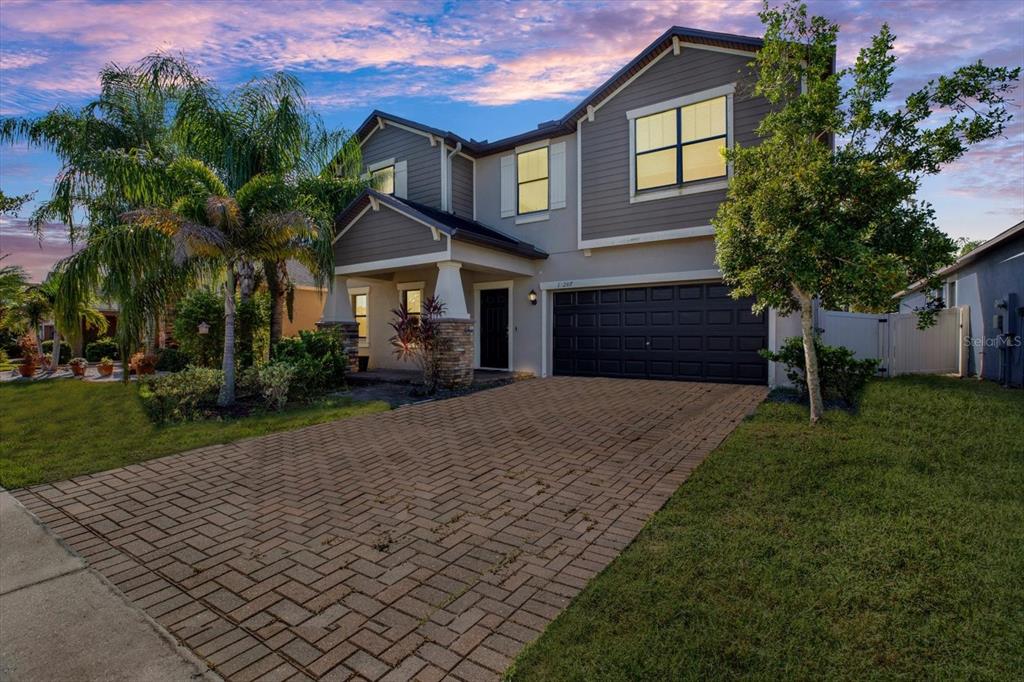 A two-story house with a brick driveway, dark garage door, and gray horizontal siding — 10207 COUNT FLEET DRIVE, RUSKIN, FL
