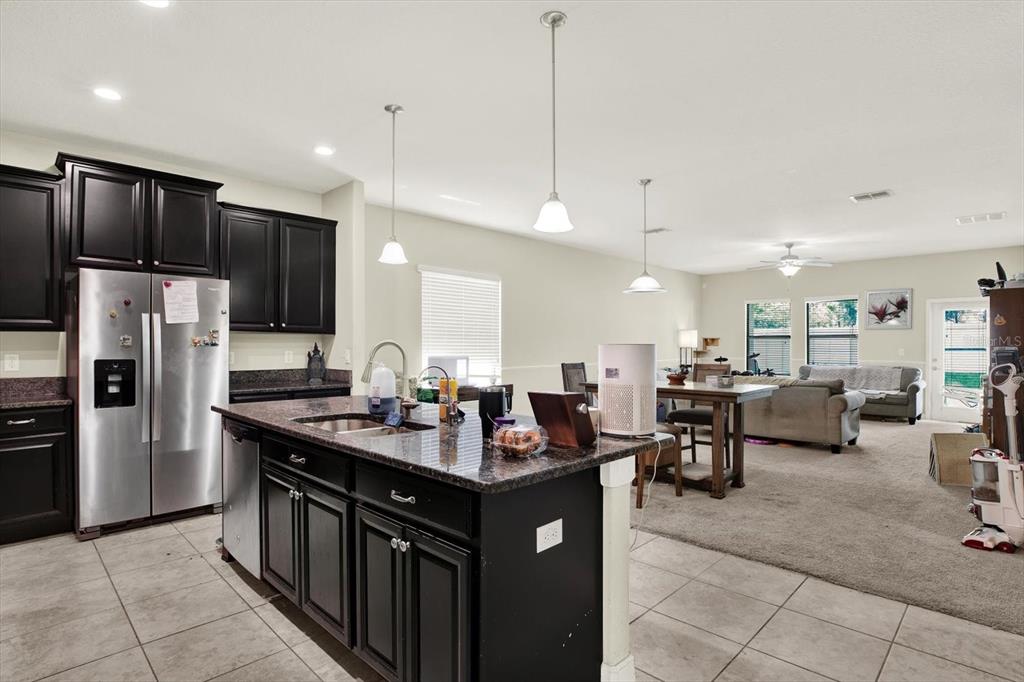 A kitchen with dark cabinets and a granite island overlooks an open-concept living area — 10207 COUNT FLEET DRIVE, RUSKIN, FL