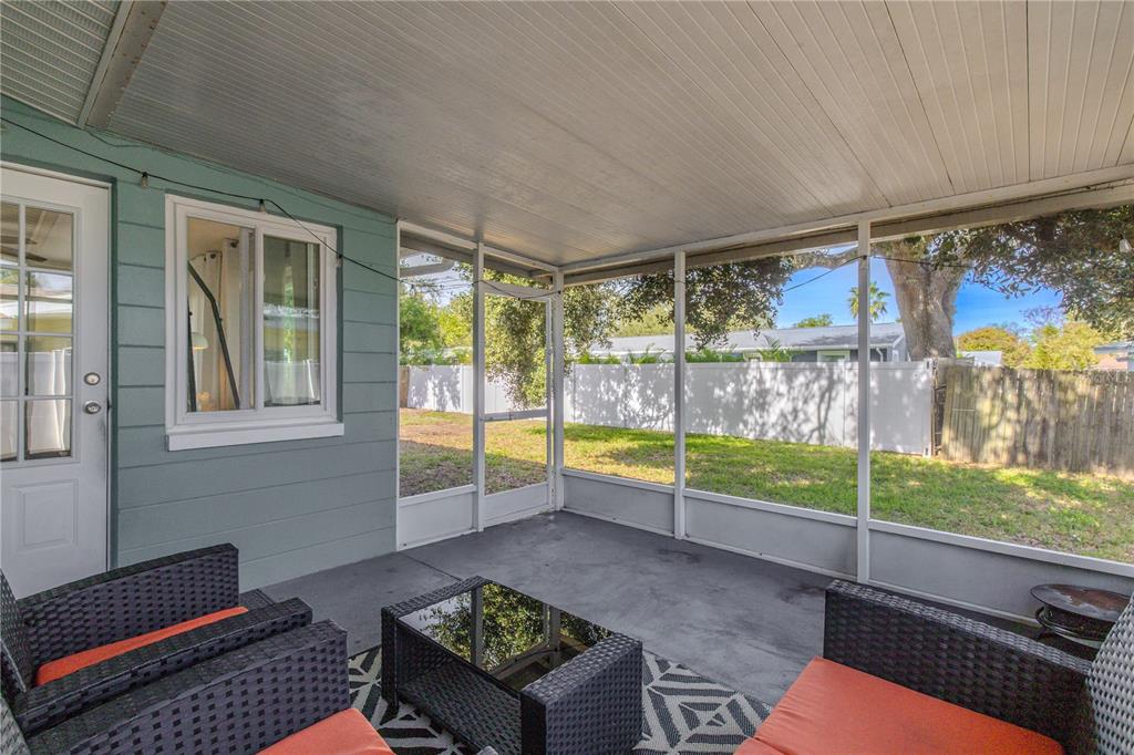A screened-in porch with gray siding, a concrete floor, and outdoor furniture overlooking a backyard — 11615 PARK BOULEVARD, SEMINOLE, FL