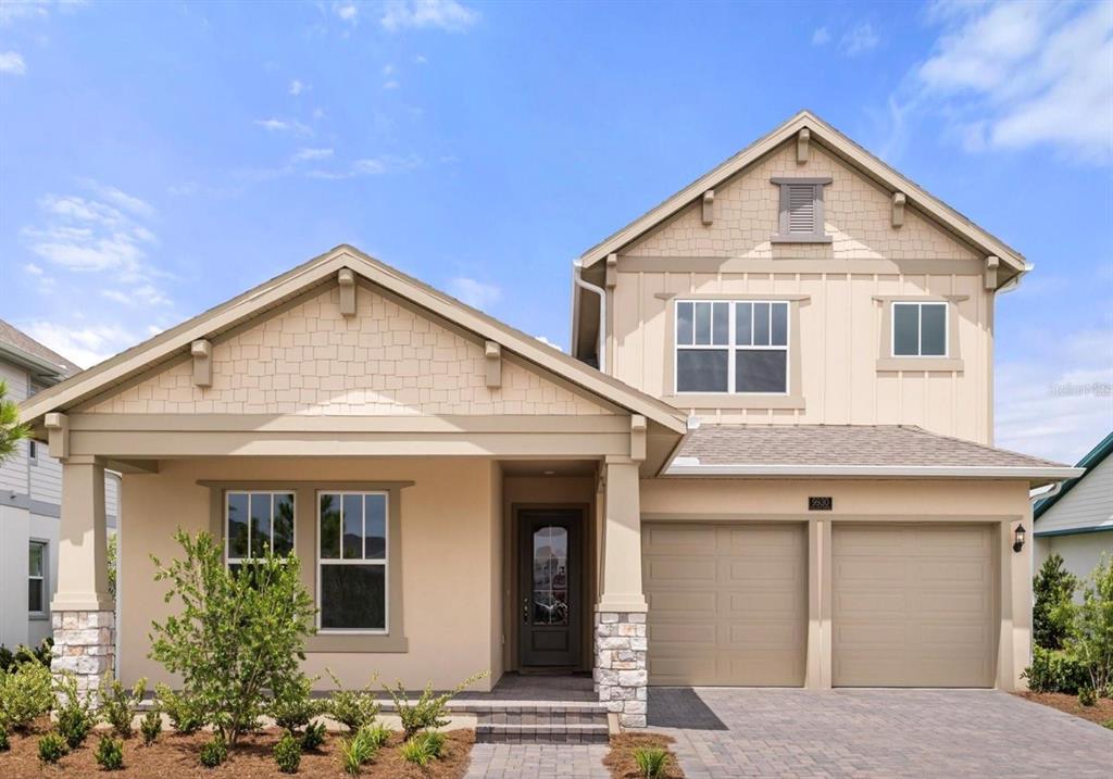 A two-story house with a beige stucco exterior, stone accents, and a two-car garage — 9930 BALLAST DRIVE, ORLANDO, FL