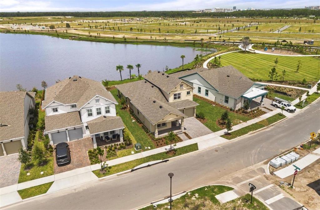 An aerial view shows three suburban houses situated along a lake and a grassy park — 9930 BALLAST DRIVE, ORLANDO, FL