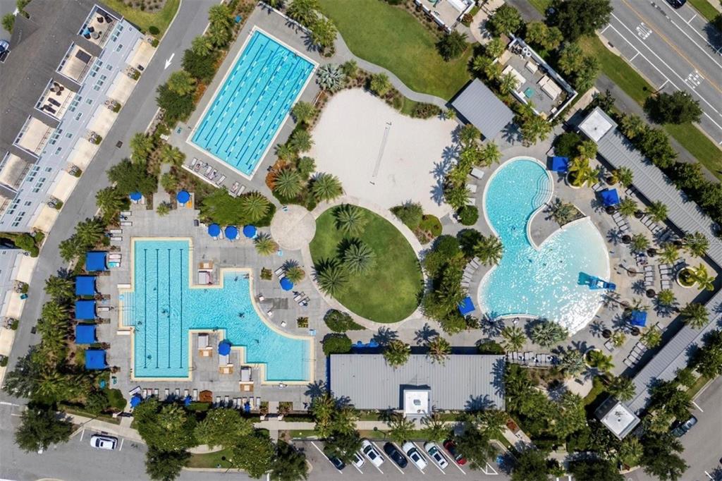 Aerial view of a community recreation area featuring multiple swimming pools, a volleyball court, and parking — 9930 BALLAST DRIVE, ORLANDO, FL