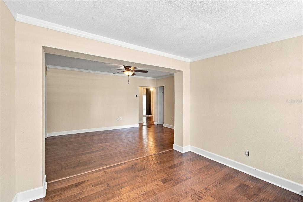 An interior view shows two connected rooms with light-colored walls and dark wood flooring — 805 W BRADDOCK STREET, TAMPA, FL