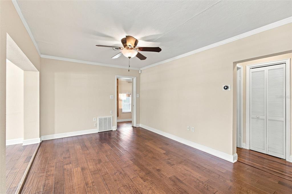 An empty room with hardwood floors, a ceiling fan, and white louvered closet doors — 805 W BRADDOCK STREET, TAMPA, FL