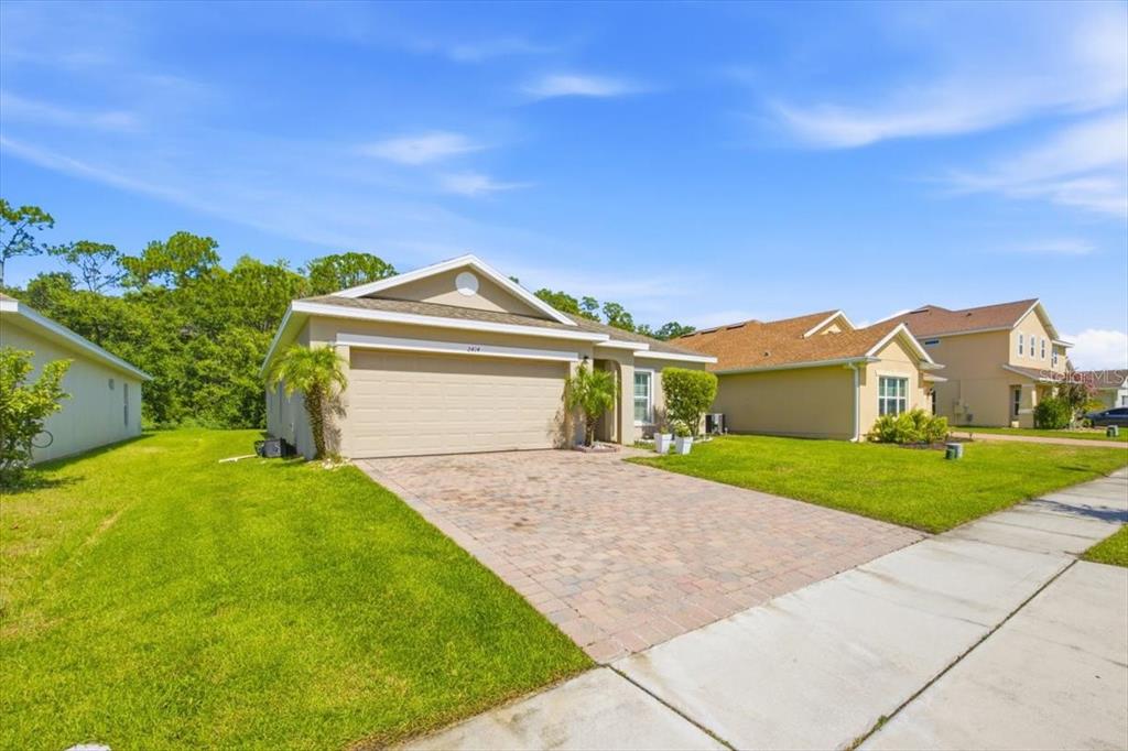 A single-story house with a beige exterior, a two-car garage, and a paved driveway — 2414 ADDISON CREEK DRIVE, KISSIMMEE, FL