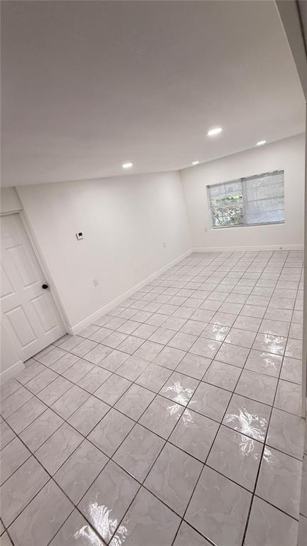 An empty room features white walls, recessed lighting, and light-colored square floor tiles — 7332 N CEDAR POINT DRIVE N UNIT 1, NEW PORT RICHEY, FL