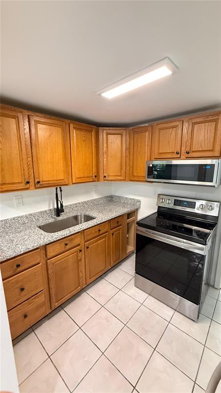 A kitchen with oak cabinets, granite countertops, and stainless steel appliances over tiled floors — 7332 N CEDAR POINT DRIVE N UNIT 1, NEW PORT RICHEY, FL