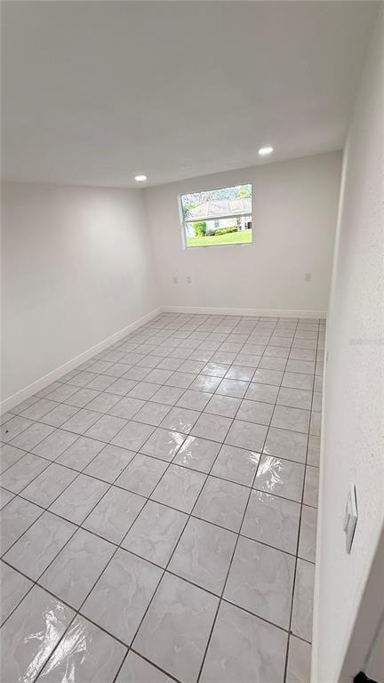An empty room with white walls, recessed lighting, and light-colored square floor tiles — 7332 N CEDAR POINT DRIVE N UNIT 1, NEW PORT RICHEY, FL