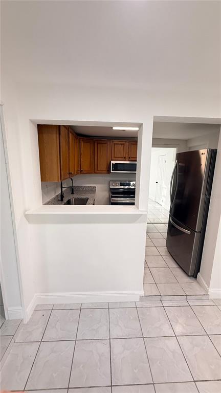 A kitchen with wood cabinets and stainless steel appliances is viewed through a wall cutout — 7332 N CEDAR POINT DRIVE N UNIT 1, NEW PORT RICHEY, FL