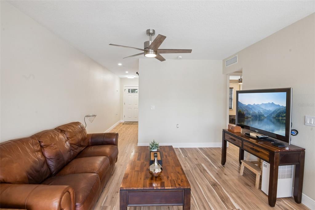 A living room features a brown leather sofa, wood coffee table, and television on a console — 609 WESTWINDS DRIVE UNIT 4, PALM HARBOR, FL