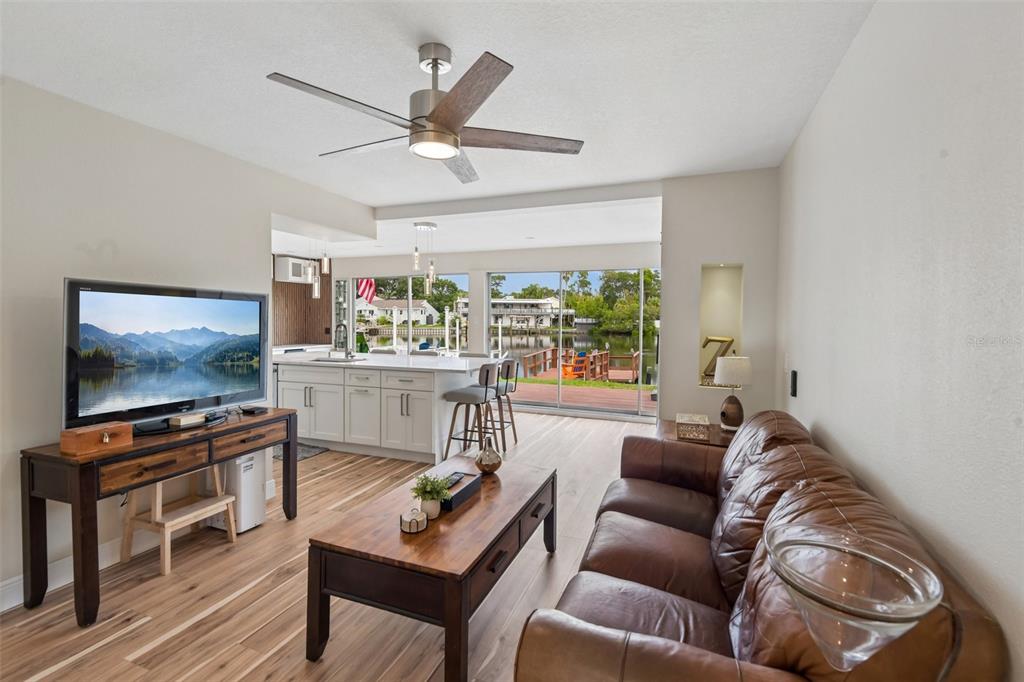 A living room with a leather sofa, wood coffee table, and kitchen overlooking a canal — 609 WESTWINDS DRIVE UNIT 4, PALM HARBOR, FL
