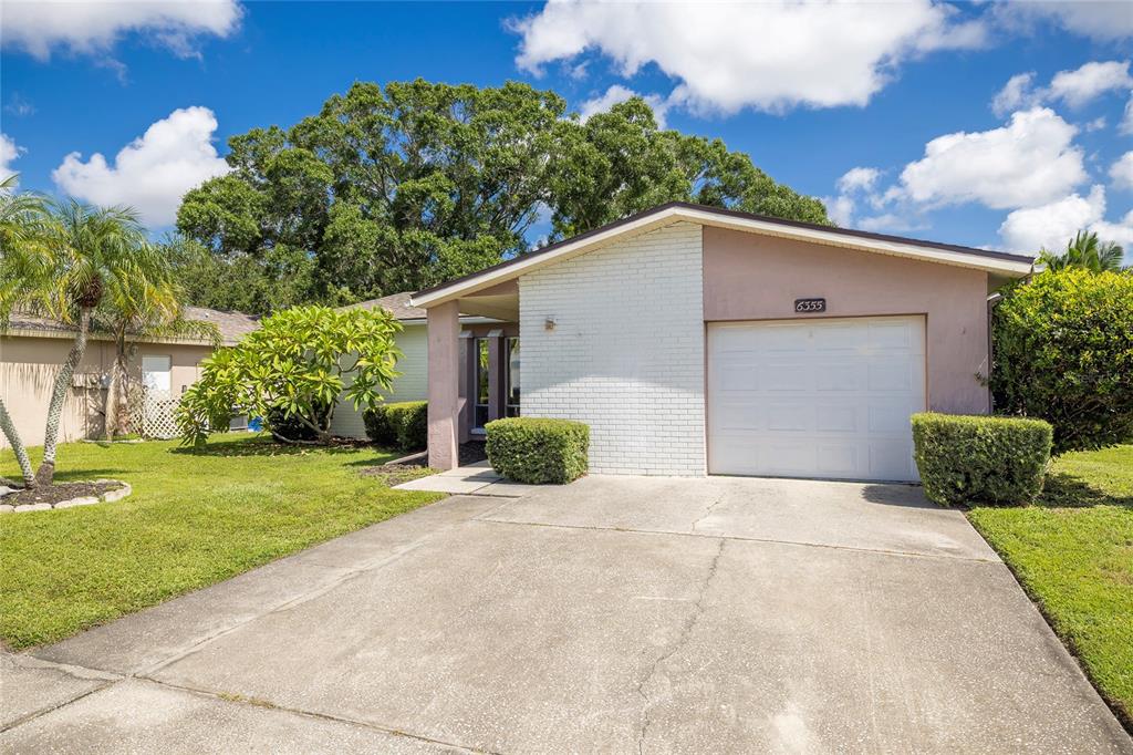 A single-story house with a white brick facade, a garage, and a concrete driveway — 6355 102ND TERRACE N, PINELLAS PARK, FL