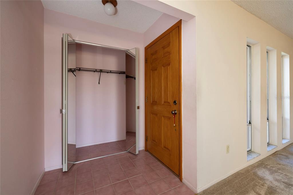 An entryway features a tiled floor, a mirrored closet, and a wooden front door — 6355 102ND TERRACE N, PINELLAS PARK, FL