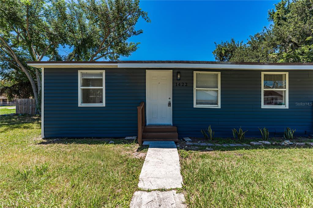 A single-story house with dark blue horizontal siding, a white front door, and three windows — 1422 BASIN STREET, WINTER GARDEN, FL