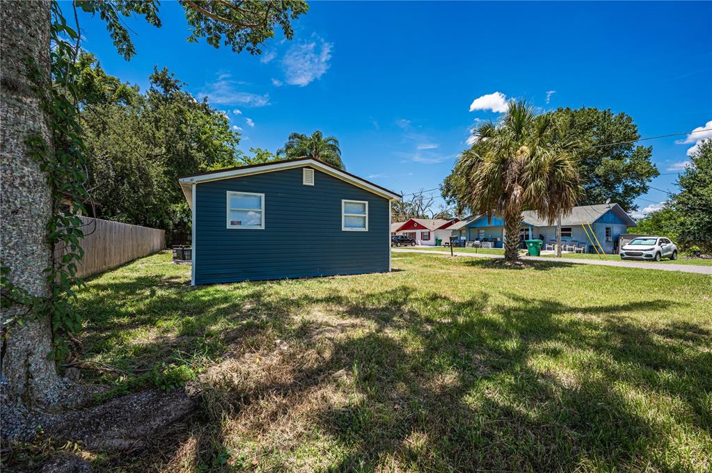 A blue-sided detached structure sits on a grassy lot near a palm tree and houses — 1422 BASIN STREET, WINTER GARDEN, FL