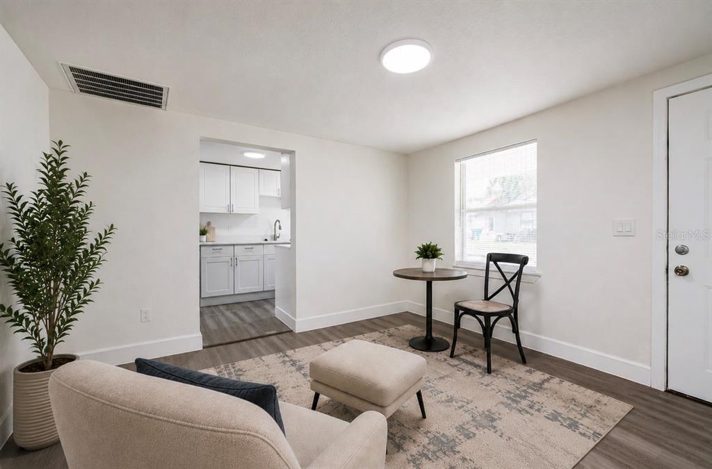 A living room with a small dining table, a chair, an ottoman, and an adjacent kitchen — 1422 BASIN STREET, WINTER GARDEN, FL