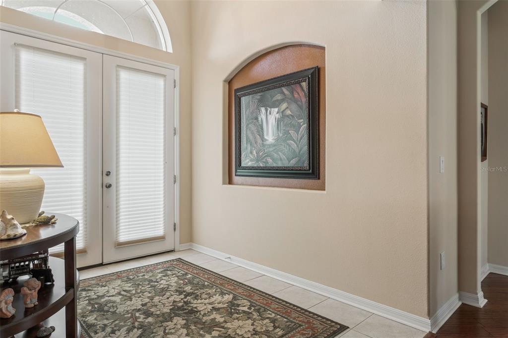 An entryway features a tiled floor, a patterned rug, a console table, and a wall niche — 1430 BEACONSFIELD DRIVE, WESLEY CHAPEL, FL