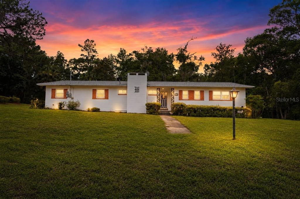 A single-story white house with a brick chimney and a large grassy front yard — 23363 NW 191ST AVENUE, HIGH SPRINGS, FL