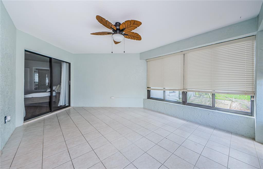 An enclosed patio features light-colored tile flooring, a ceiling fan, and large windows with blinds — 3647 MUIRFIELD COURT, NEW PORT RICHEY, FL