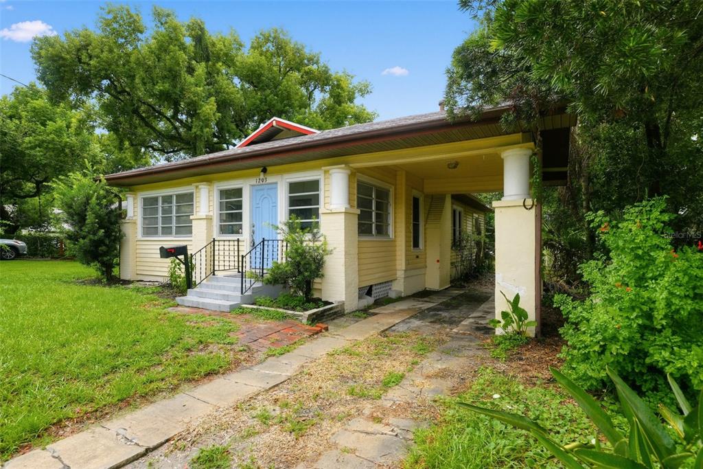 A yellow single-story house with a front porch, a carport, and a blue front door — 1203 KING AVENUE, LAKELAND, FL
